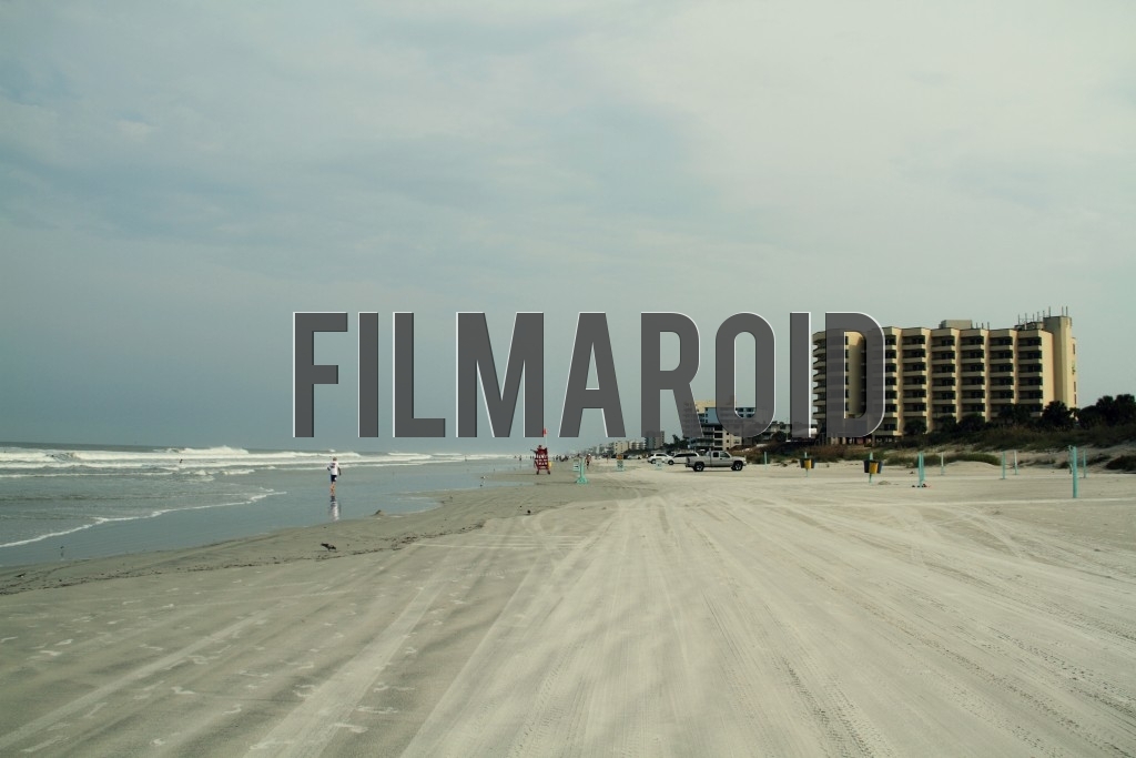 Atmosphere in a beach in Florida Atmosphere in a beach in Florida - Landscape of a beach in Florida with waves buildings and people seen far in the distance