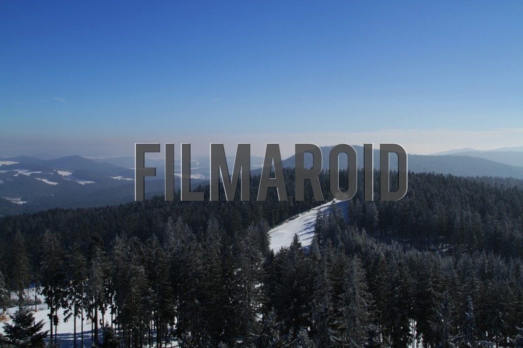 Dramatic blue sky over a beautiful winter landscape portraying several hills and a ski track