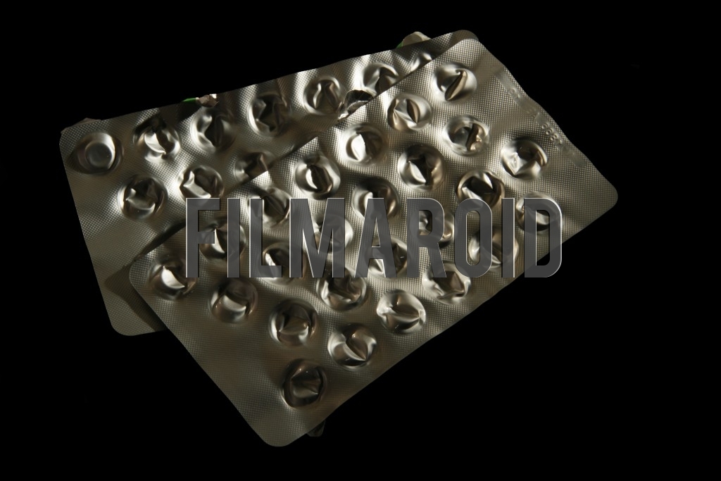 An isolated pair of empty pack of pills An isolated pair of empty pack of pills - A pair of isolated empty shiny aluminum packs of pills against a pitch black background