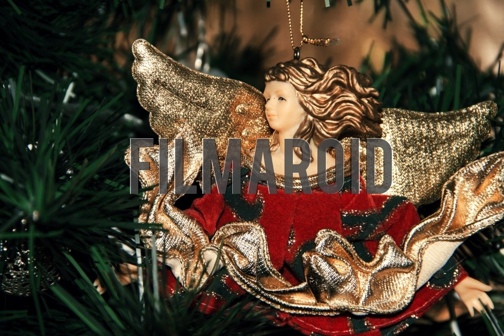 A red Christmas tree ornament of an angel with golden wings
