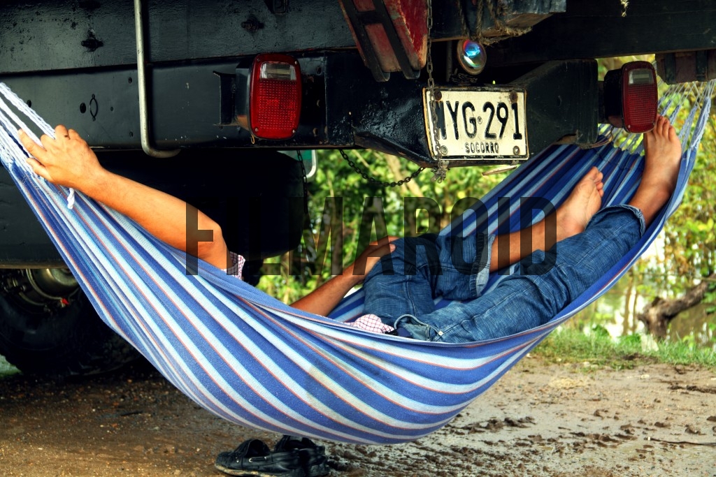 Man sleeping in hammock under truck Man sleeping in hammock under truck - A man comfortably sleeping in a hammock under a truck