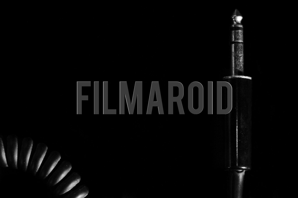 Closeup view of a vintage quarter inch jack connector with curled cable against pitch black background