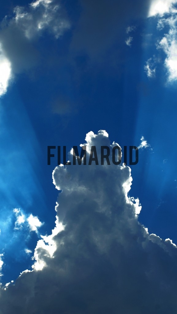 Intense blue sky with large cloud and rays of light coming from the back