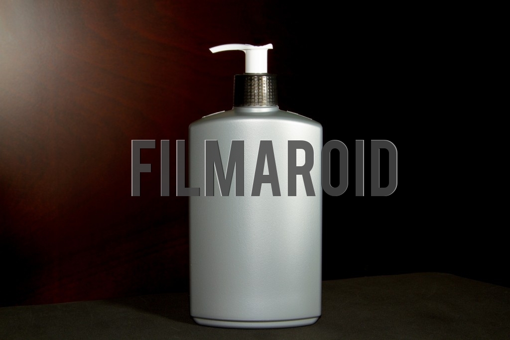 Large plastic bottle with dispenser for body lotion Large plastic bottle with dispenser for body lotion - Isolated large gray plastic bottle ideal for body lotion or hands gel against a wooden background