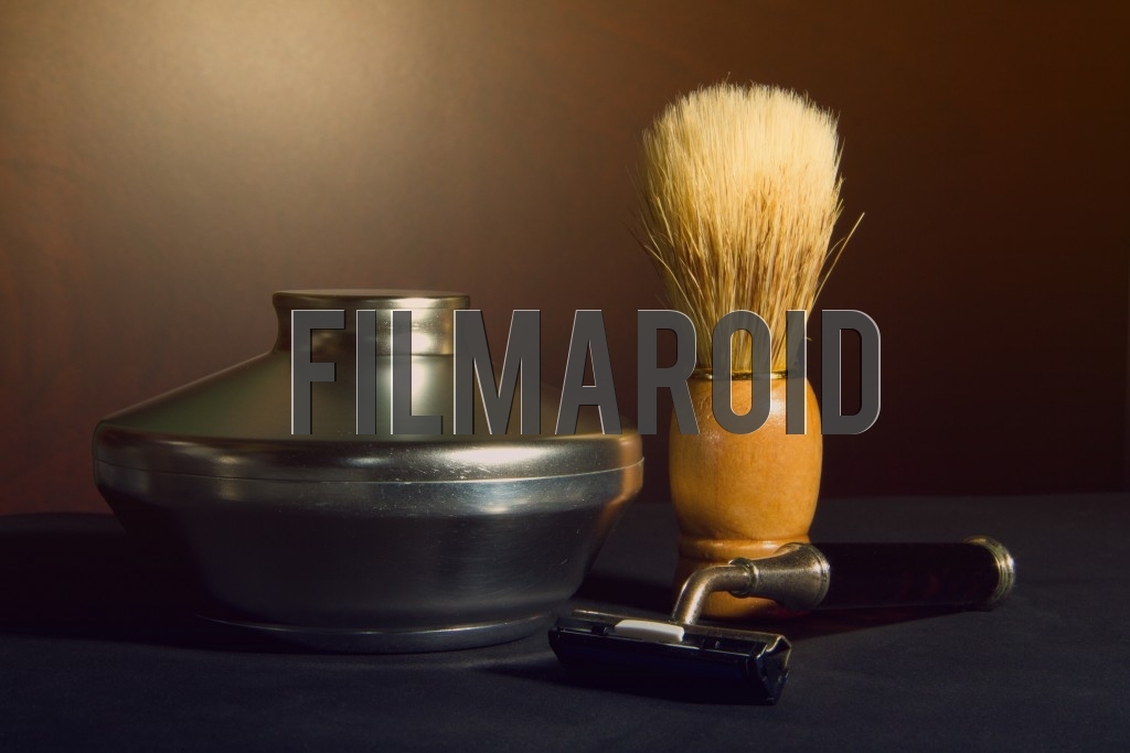 Beautiful vintage shaving kit with razor and camel hair brush against an organic brown wooden background